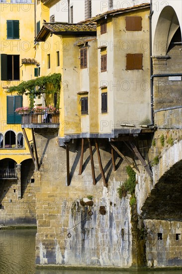 ITALY Tuscany Florence Ponte Vecchio medieval bridge across River Arno. View of merchant's shops that line bridge and hang over the water below