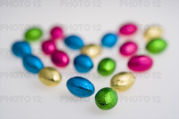 Food, Sweets, Chocolate, Colourful foil wrapped Easter eggs in the shape of a Valentine heart on a white background.