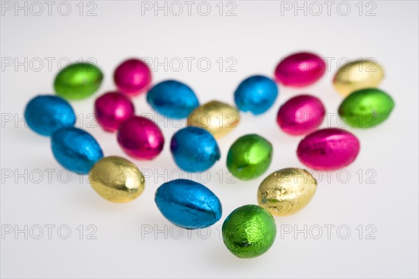 Food, Sweets, Chocolate, Colourful foil wrapped Easter eggs in the shape of a Valentine heart on a white background.