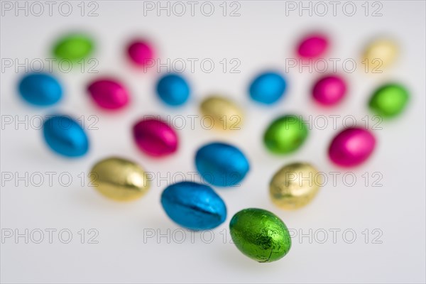 Food, Sweets, Chocolate, Colourful foil wrapped Easter eggs in the shape of a Valentine heart on a white background.