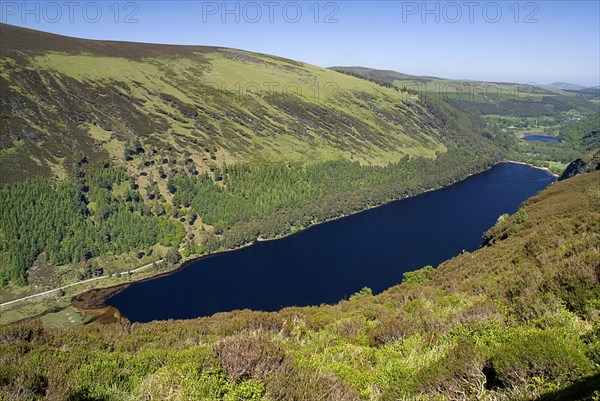 IRELAND, County Wicklow, Glendalough, Vista of the Upper lake from the Spink Trail with Lower Lake and Round Tower in far distance.