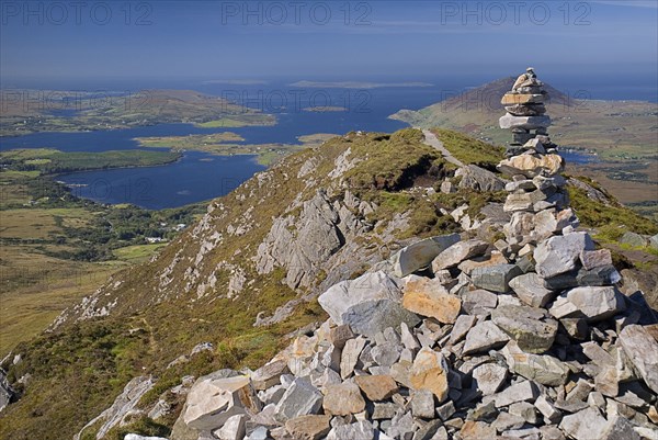 IRELAND, County Galway, Connemara, Diamond Hill, Stone pile at the summit of the hill with Ballynakill Harbour below.