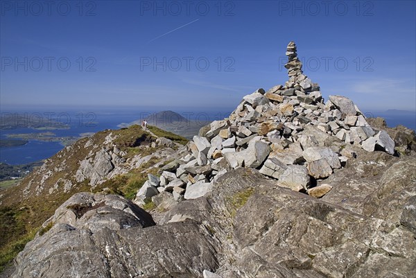 IRELAND, County Galway, Connemara, Diamond Hill, two hikers approach the stone pile at the summit.