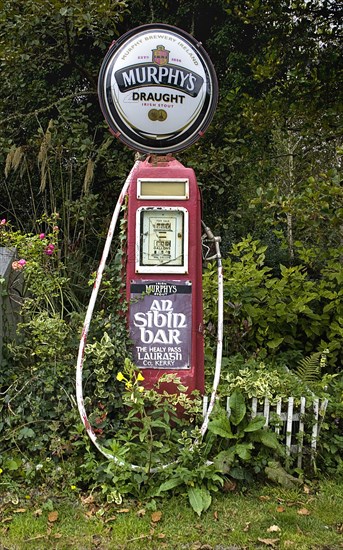 IRELAND, County Kerry, Lauragh Village, Murphys stout sign affixed to old petrol pump with advert for bar.