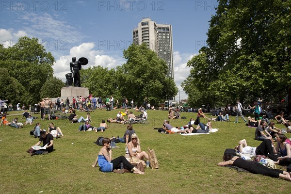 ENGLAND, London, Hyde Park, People sunbathing on a sunny day with blue sky and white clouds, at Hyde Park just in front of Achilles statue, while they are waiting for the world naked bike ride parade to start.