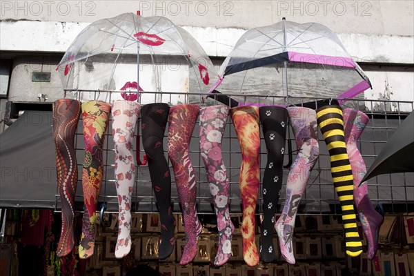 ENGLAND, London, Camden Town, Fake legs with colorful tights and open umbrellas above them, hanged on a wall as part of a shops decoration at famous Camden Town market.