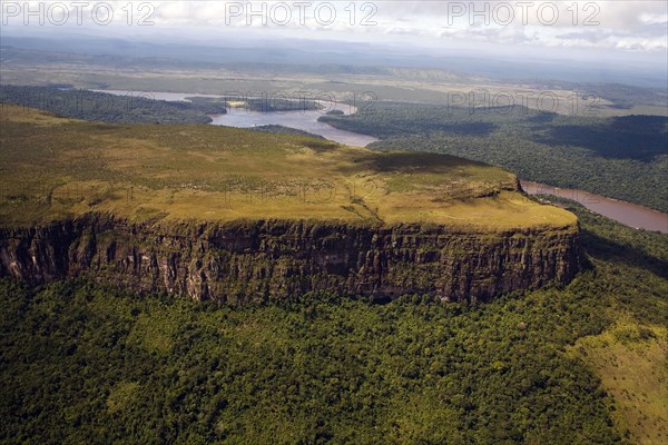 VENEZUELA, Bolivar State, Canaima National Park, Tepui mountain surrounded by a forest and a river shoot from above