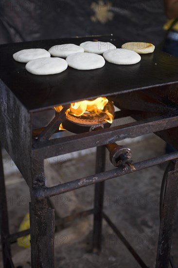 VENEZUELA, Bolivar State, Ciudad Bolivar, Handmade pancakes on a metal big plate with fire underneath them are being baked, at the street of Ciudad Bolivarís historical centre.