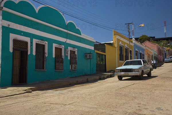 VENEZUELA, Bolivar State, Ciudad Bolivar, Colorful, candy like, buildings and an old American car in front of them shoot on a bright day with blue sky at Ciudad Bolivarís old historical centre.