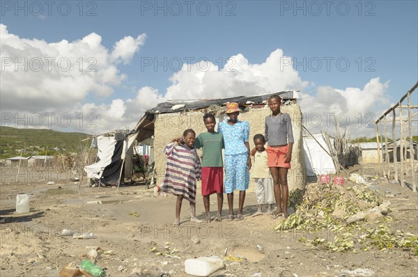 HAITI, Isla de la Laganave, family stood outside their shack in slum area.