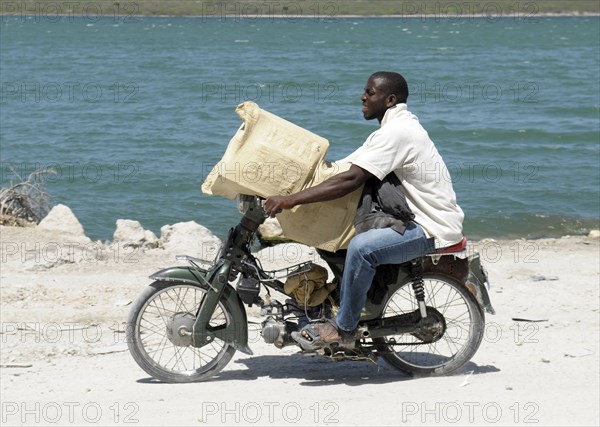 Haiti, Isla de Laganave, Man transporting goods on motorcycle.