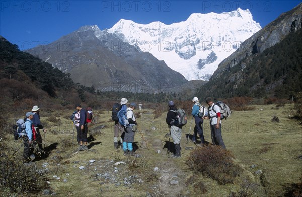 BHUTAN, Snowman Trek, Group of travellers hiking on a trail near Limithang beneath Mount Gangcheta Great Tiger Mountain.