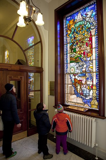 Ireland, North, Belfast, City Hall, Interior,Tourists viewing Centenary Stained Glass Window with various scenes depicted including the construction of Titanic at Harland & Wolf shipyard.