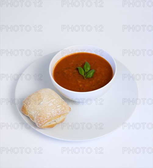 Food, Cooked, Soup, Bowl of tomato and basil soup on a plate with a rustic bread roll on a white background.