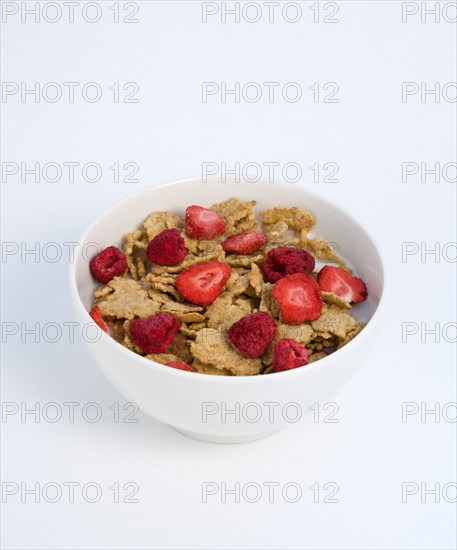 Food, Meals, Cereals, White breakfast bowl of bran flake cereal with freeze dried fruits of strawberries and raspberries in milk on a white background.
