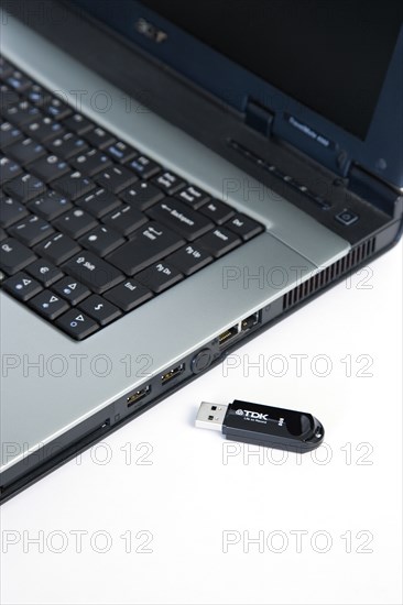 Industry, Computers, Components, 8 gigabyte portable USB flash drive storage device beside laptop computer USB port.