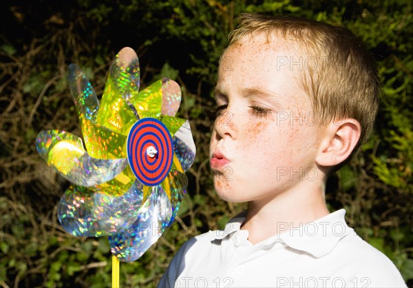 Children, Toys, Outdoors, Young boy blowing toy windmill gently.