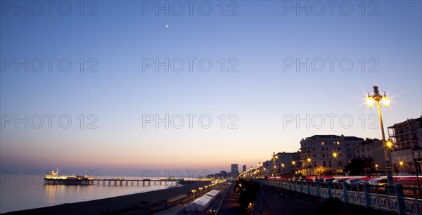 England, East Sussex, Brighton, Kemptown, view over Madeira Drive from Marine Parade with the pier illuminated at sunset. Skies clear due to no fly zone over uk because of Icelandic volcanic dust fears.