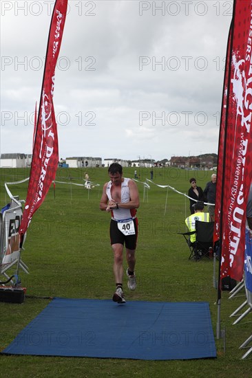 England, West Sussex, Goring-by-Sea, Worthing Triathlon 2009, male competitor checking his watch at finish line.