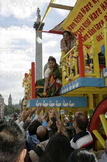 Religion, Hindu, Worship, London Rathayatra celebrations in Trafalgar Square. People handing out offerings during festival. Nelsons Column behind.