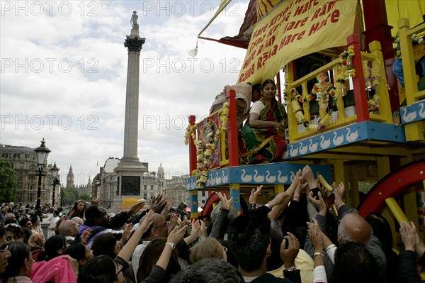 Religion, Hindu, Worship, London Rathayatra celebrations in Trafalgar Square. People handing out offerings during festival. Nelsons Column behind.