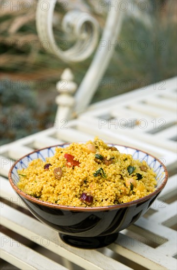 Food, Cooked, Pasta, Bowl of Moroccan couscous with fruit nuts and vegetables on a metal table in a garden.