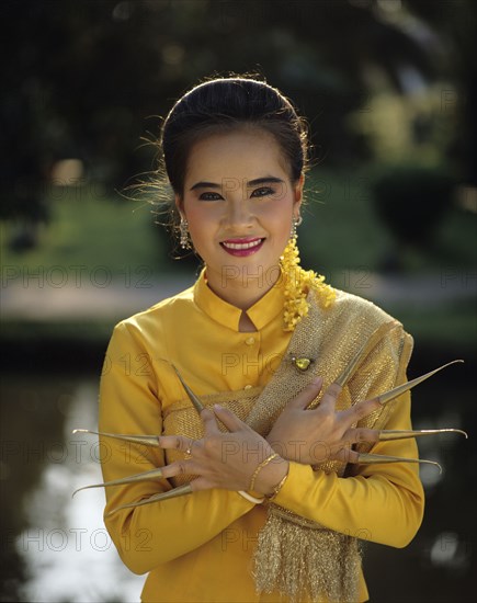 Thailand, woman in traditional dress with nail extensions.