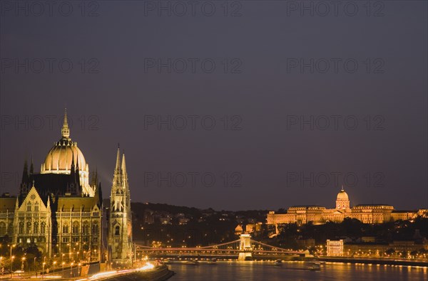 Hungary, Budapest, View along the River Danube at night with the Parliament building on the left, the Chain Bridge and the Royal Palace on the right all illuminated brightly.