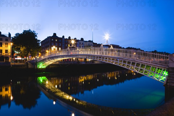 Ireland, County Dublin, Dublin City, The 1816 cast iron Ha Penny or Half Penny Bridge across the River Liffey illuminated at sunset.