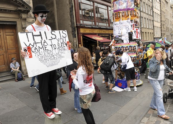 Scotland, Lothian, Edinburgh Fringe Festival of the Arts 2010, Street performers and crowds on the Royal Mile, mime artists advertising upcoming show.