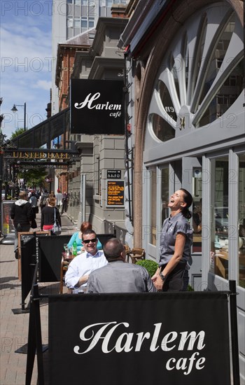 Ireland, North, Belfast, Bedford street, waitress enjoying a joke with customers outside Harlem cafe.