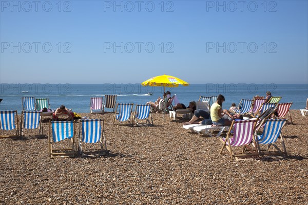 England, East Sussex, Brighton, Deck chairs and sunbathers on the pebble beach.