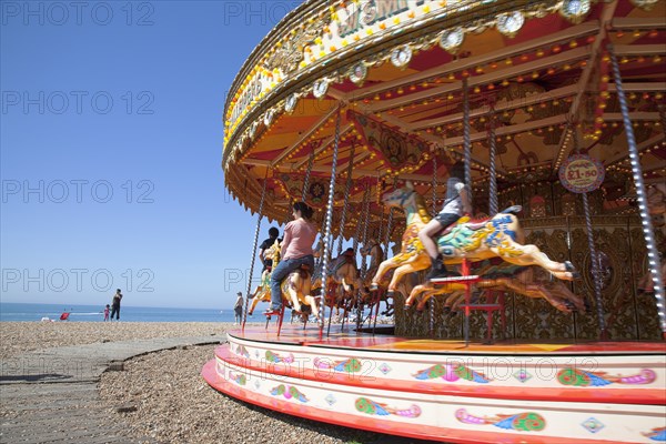 England, East Sussex, Brighton, Carousel on the pebble beach promenade.