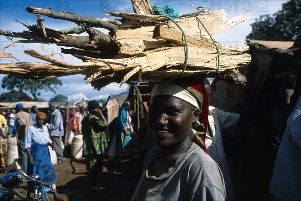 Great Lakes Region, West, Tanzania. Refugee woman carrying bundle of firewood on her head. Refugees from the Congo and Rwanda fleeing conflict in Burundi Zaire African Burundian Central Africa Eastern Africa Female Women Girl Lady Rwandan Tanzanian Uburundi Zairean