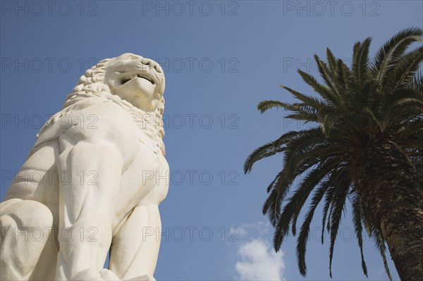 Samos Island, Northern Aegean, Greece. Vathy. Lion statue in Pythagoras Square set up in 1930 to mark the centenary of the uprising against the Ottoman Turkish overlords. Greece Greek Europe European Vacation Holiday Holidays Travel Destination Tourism Ellas Hellenic Northern Aegean Samos Vathy Lion Statue Art Carved Pythagoras Square Architecture Blue Sky Palm Tree Destination Destinations Ellada History Historic Southern Europe