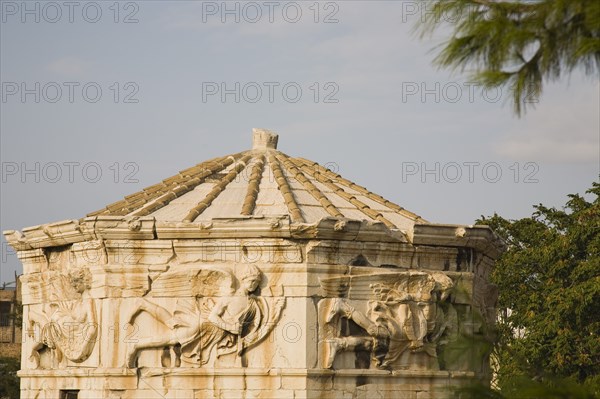 Athens, Attica, Greece. Tower of the Winds on the Roman Agora in Athens. Part view of octagonal Pentelic marble clocktower with frieze depicting the wind gods. Greece Greek Europe European Vacation Holiday Holidays Travel Destination Tourism Ellas Hellenic Attica Athens Agora Roman Ruin Architecture Building Tower Winds Octagonal Pentelic Marble Stone Clocktower Facade Frieze God Gods Atenas Athenes Destination Destinations Ellada History Historic Religion Southern Europe