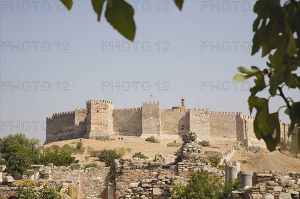 Selcuk, Izmir Province, Turkey. The grand fortress of Selcuk on Ayasoluk Hill with crenellated walls and towers. Ancient ruins in foreground. Turkey Turkish Eurasia Eurasian Europe Asia Turkiye Izmir Province Selcuk Ayasoluk Hill Grand Fort Fortress Ruin Ruins Wall Walled Castle Tower Towers Crenellated Castillo Castello Destination Destinations European History Historic Middle East South Eastern Europe Western Asia