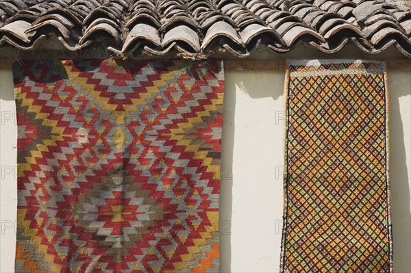 Selcuk, Izmir Province, Turkey. Kilims hanging up to dry in sunshine on walls of village house. Turkey Turkish Eurasia Eurasian Europe Asia Turkiye Izmir Province Selcuk Kilim Kilims Rug Rugs Carpet Carpets Hanging Roof Tiles Slates Destination Destinations European Middle East South Eastern Europe Western Asia