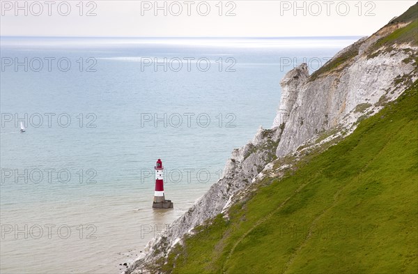 Eastbourne, East Sussex, England. Beachy Head view of the lighthouse at the base of the chalk cliffs. England English UK United Kingdom GB Great Britain Birtish East Sussex County Eastbourne Beachy Head Sea Coast Chalk Cliff Cliffs White Lighthouse Light House Boat Ship Transport Warning