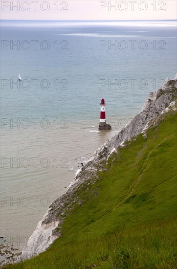 Eastbourne, East Sussex, England. Beachy Head view of the lighthouse at the base of the chalk cliffs. England English UK United Kingdom GB Great Britain Birtish East Sussex County Eastbourne Beachy Head Sea Coast Chalk Cliff Cliffs White Lighthouse Light House Boat Ship Transport Warning