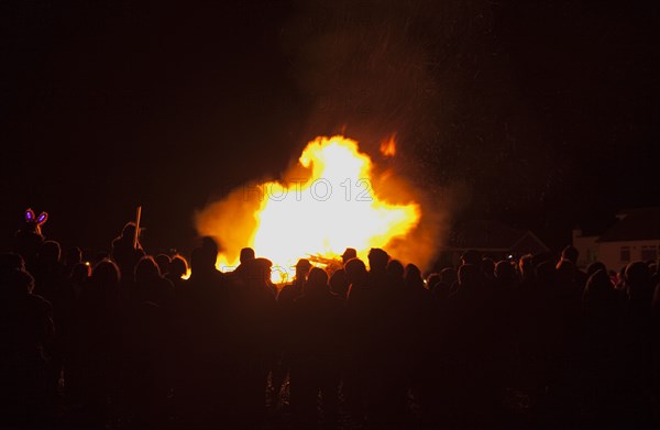 Shoreham Beach, West Sussex, England. Festivals Guy Fawkes Bonfire People silhouetted by flames from fire on the beach. Festival Festivals Bonfire Night Guy Fawkes Flame Flames People Group Crowd Revellers Silhouette Silhouetted Fire Orange Yellow Black