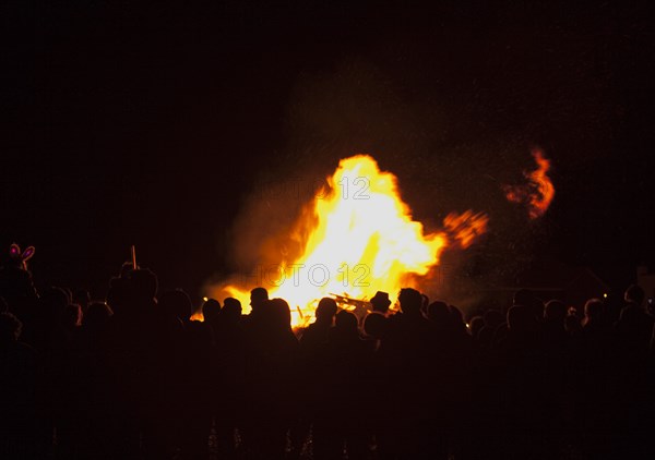 Shoreham Beach, West Sussex, England. Festivals Guy Fawkes Bonfire People silhouetted by flames from fire on the beach. Festival Festivals Bonfire Night Guy Fawkes Flame Flames People Group Crowd Revellers Silhouette Silhouetted Fire Orange Yellow Black