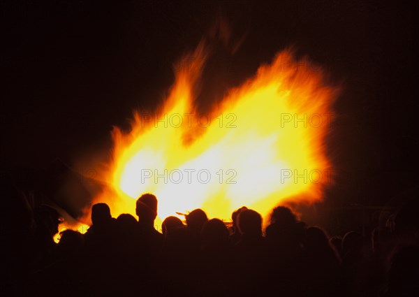 Shoreham Beach, West Sussex, England. Festivals Guy Fawkes Bonfire People silhouetted by flames from fire on the beach. Festival Festivals Bonfire Night Guy Fawkes Flame Flames People Group Crowd Revellers Silhouette Silhouetted Fire Orange Yellow Black