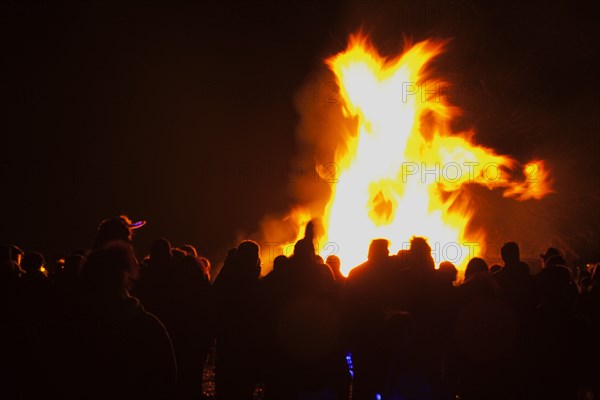 Shoreham Beach, West Sussex, England. Festivals Guy Fawkes Bonfire People silhouetted by flames from fire on the beach. Festival Festivals Bonfire Night Guy Fawkes Flame Flames People Group Crowd Revellers Silhouette Silhouetted Fire Orange Yellow Black