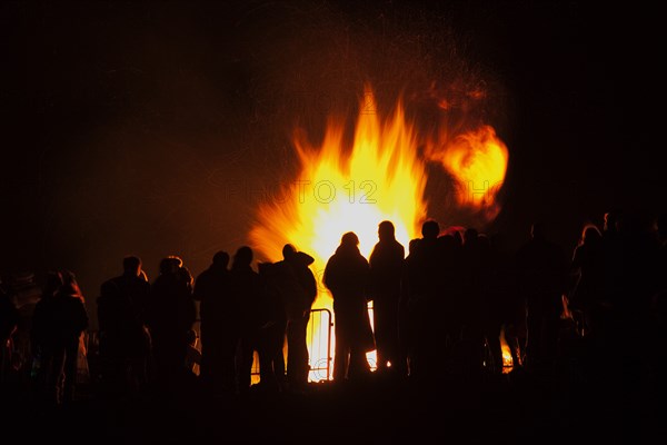 Shoreham Beach, West Sussex, England. Festivals Guy Fawkes Bonfire People silhouetted by flames from fire on the beach. Festival Festivals Bonfire Night Guy Fawkes Flame Flames People Group Crowd Revellers Silhouette Silhouetted Fire Orange Yellow Black