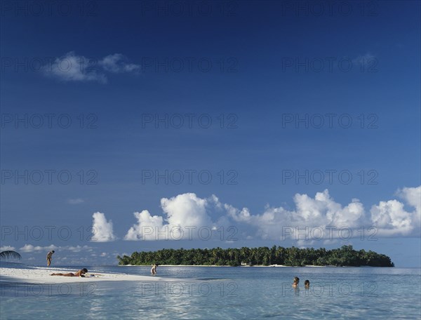 Beach, Maldives. Beach with tourist sunbathing and swimming in the Indian Ocean. Maldives Island Islands Paradise Holiday Sea Water Travel Calm Blue Sky Beach Sand Shore Coast Indian Ocean Asia Asian Palm Trees Clear Vacation Tourists Color Destination Destinations Divehi Rajje Holidaymakers Sand Sandy Beaches Tourism Seaside Shore Tourist Tourists Vacation Sightseeing Sunbather