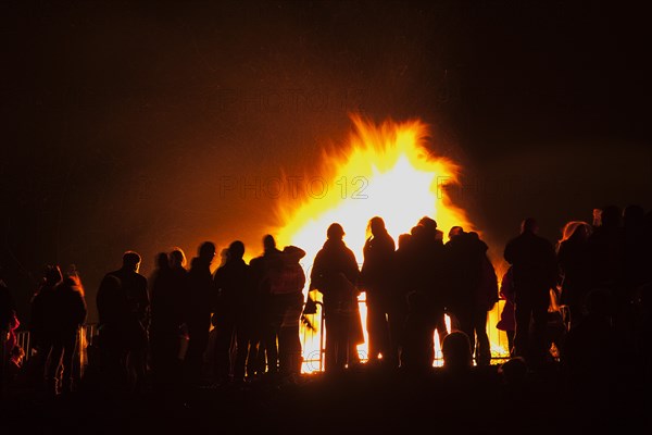 Shoreham Beach, West Sussex, England. Festivals Guy Fawkes Bonfire People silhouetted by flames from fire on the beach. Festival Festivals Bonfire Night Guy Fawkes Flame Flames People Group Crowd Revellers Silhouette Silhouetted Fire Orange Yellow Black