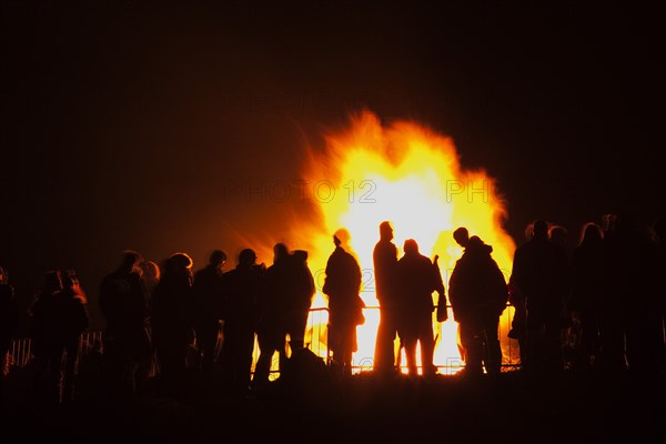 Shoreham Beach, West Sussex, England. Festivals Guy Fawkes Bonfire People silhouetted by flames from fire on the beach. Festival Festivals Bonfire Night Guy Fawkes Flame Flames People Group Crowd Revellers Silhouette Silhouetted Fire Orange Yellow Black