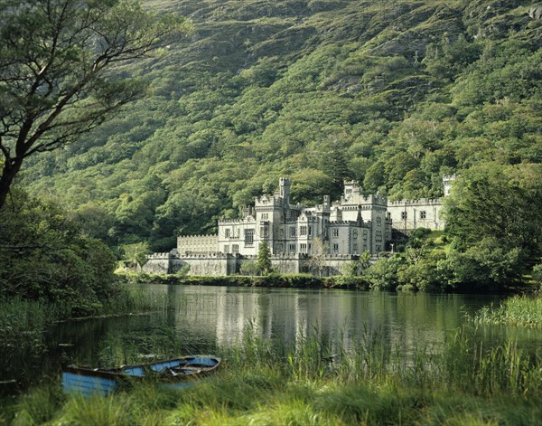 Connemara, County Galway, Ireland. Kylemore Abbey with lake in the foreground. Ireland Irish County Galway Connemara Kylemore Abbey Architecture Building Trees Landscape Rural Lake Water Europe European Boat Color Destination Destinations Eire History Historic Northern Europe Religion Religious Republic Scenic