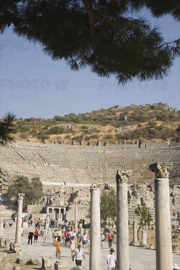 Selcuk, Izmir Province, Turkey. Ephesus. Crowds of tourists visiting ancient city of Ephesus on the Aegean sea coast with amphitheatre part seen behind. Turkey Turkish Eurasia Eurasian Europe Asia Turkiye Izmir Province Selcuk Ephesus Ruin Ruins Masonry Rock Stone Tourists Amphitheater Amphitheatre Destination Destinations European History Historic Holidaymakers Middle East South Eastern Europe Tourism Water Western Asia